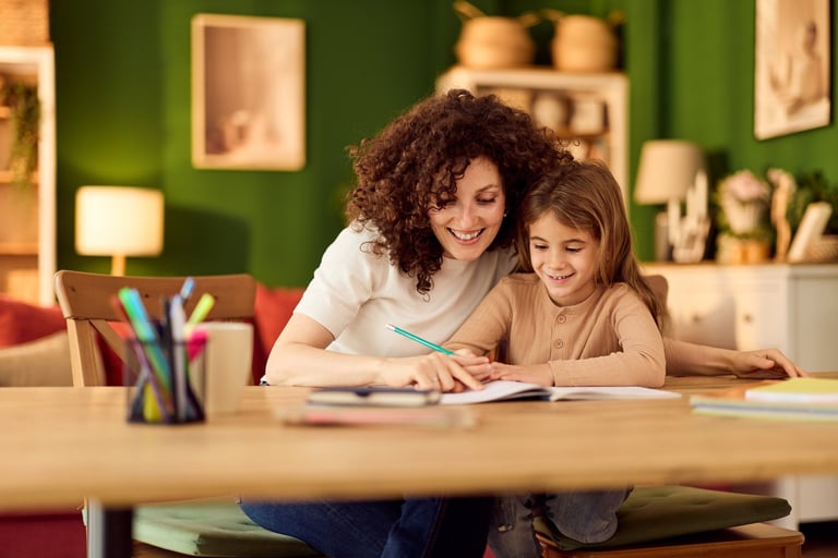 Warm, happy moment of mom helping daughter with homework at a cozy kitchen table