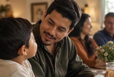 Man smiling while talking to a young boy at a family gathering indoors